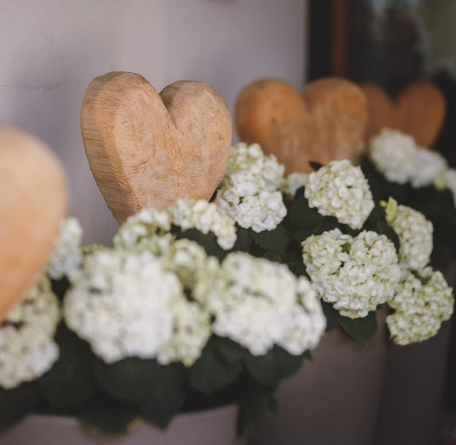 Holzherzen und weiße Blumen in einer Dekoration.