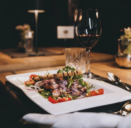 Ein Teller mit Salat, gegrilltem Fleisch und Gemüse, im Restaurantambiente.