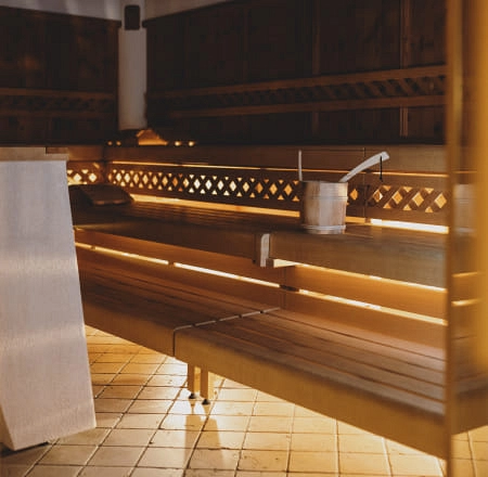 Innenansicht einer Sauna mit hölzernen Bänken und einem Eimer.