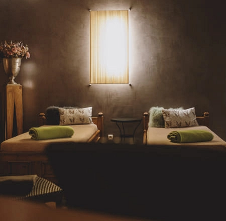 Helle Zimmer mit zwei Betten, dekoriert mit grünen Handtüchern und einer Lampe.
