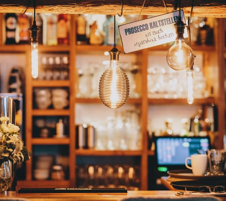 Gemütliche Bar mit warmen Lichtern und Prosecco-Schild
