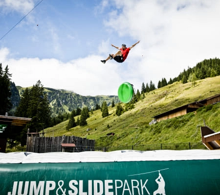Person springt im Jump & Slide Park mit grünem Schlauch